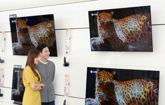 30일 LG전자 모델들이 서울 영등포구에 위치한 LG 베스트샵 매장에서 'LG 올레드(OLED) TV'를 살펴보고 있다.  LG전자 제공